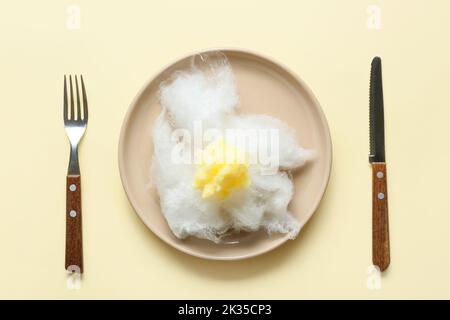 Composition with table setting and sweet cotton candy in shape of fried egg on yellow background Stock Photo