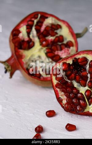 close up of a cut pomegranate on white table with texture Stock Photo