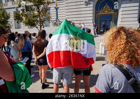 Protesters gather outside the city hall with the flag of Iran during the demonstration. After the death of the young Iranian girl Mahsa Amini, protests and demonstrations appeared in different cities of Iran. Outside Iran, protests and rallies to support people in Iran also happen across the world. In San Francisco, a few people protested outside the San Francisco City Hall. The protesters say they want to express their voice to the Iranians and let them know there are many people support them in the world. Also, there are some Iranians join the protest and speak on the protest. Stock Photo