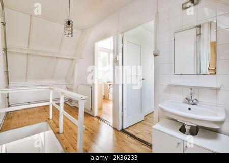 Interior of narrow corridor with telephone and radiator hanging on wall against stairway in daylight Stock Photo