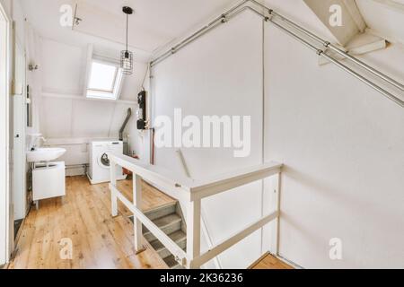 Interior of narrow corridor with telephone and radiator hanging on wall against stairway in daylight Stock Photo