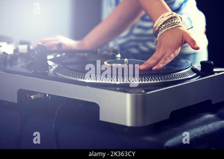 Mixing up the perfect musical offering. Cropped view of a DJ mixing music on a turntable. Stock Photo