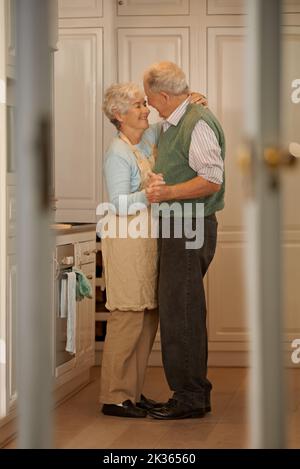 Care for a dance. Full-length shot of an elderly couple standing together in their home. Stock Photo