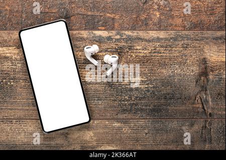 mockup modern smartphone with blank white screen. earphones and mobile phone with blank screen on copy space white background. Top view mock up , flat Stock Photo