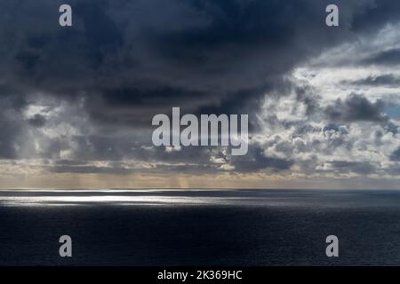 sun breaking through dark clouds over the Atlantic Ocean seen from the Irish coast in spring at the cliffs of moher Stock Photo