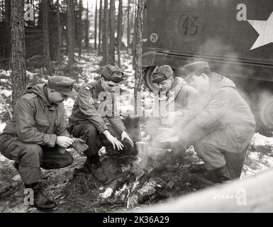 Warm Hands, Warm Chow from Field Fire Comfort American and German soldiers, Including Sgt Elvis Presley, 3rd Armored Division 32nd Armor Scouts, During US Army's Winter Shield Exercise in Bavaria, West Germany Stock Photo