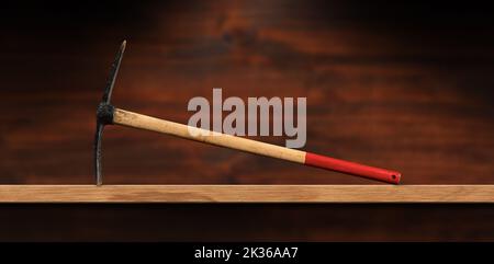 Close-up of a pickaxe or pick axe with red and brown wooden handle on a wooden workbench with copy space. Hand tool used for digging, photography. Stock Photo