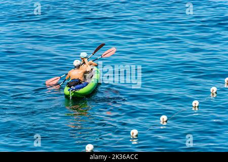 A man and a woman aboard an inflatable kayak, paddling in the blue Mediterranean sea, on a sunny summer day. Gulf of La Spezia, Liguria, Italy, Europe Stock Photo