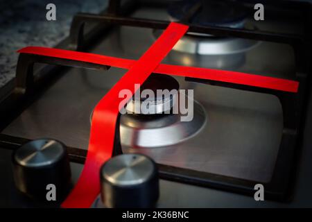 Gas stove with red ribbon criss-cross, does not work at home, in the kitchen. Unavailability of natural gas. Stock Photo