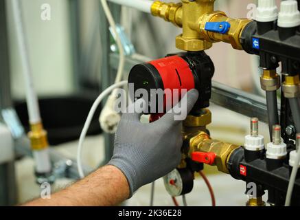 Plumber hands installing circulation pump for heating system. Stock Photo