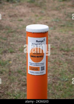 Lillo, Belgium, 31 July 2022, Orange pole with the text, Fluxys, Natural gas pipeline under high pressure, Calling only in case of incident and workin Stock Photo