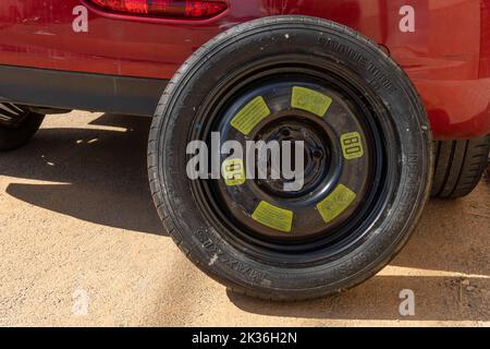 Felanitx, Spain; september 18 2022: Flat tire of a red Peugeot 208 car, together with its spare tire ready to change it Stock Photo