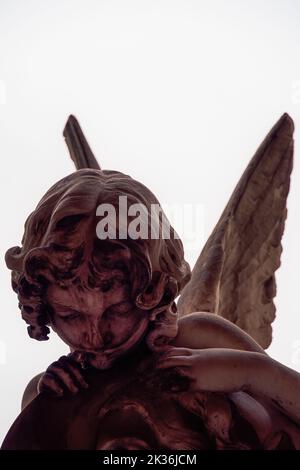 Statue figure of an angel with wings, against a white background. Stock Photo
