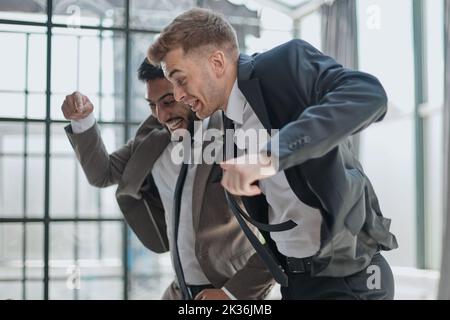 A businessmen standing with hands raised in victory and looking in laptop Stock Photo