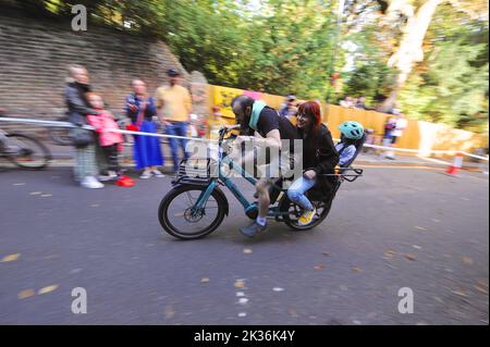 Competitors on a cargo bike racing up Swains Lane in Highgate, London during an Urban Hill Climb street racing event organised by the London Cycling Campaign, sponsored by Osbornes Law. The event is a flat-out race up the steepest street in London and alongside age and gender categories has competitions for all kinds of bike, including cargo bikes.  Swain’s Lane is the most famous and notorious climb in London. The lane is an extremely steep section of road, located in-between Hampstead Heath and Highgate Cemetery with a gradient that averages 9% over 0.6km, but increases to 14% near the top o Stock Photo