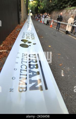Perimeter Tape on the course of the Urban Hill Climb street racing event organised by the London Cycling Campaign, sponsored by Osbornes Law. The event is a flat-out race up the steepest street in London and alongside age and gender categories has competitions for folding and cargo bikes.  Swain’s Lane is the most famous and notorious climb in London. The lane is an extremely steep section of road, located in-between Hampstead Heath and Highgate Cemetery with a gradient that averages 9% over 0.6km, but increases to 14% near the top of the climb. Stock Photo