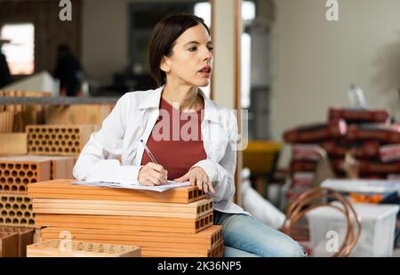 Interested brunette making notes while planning home renovation Stock Photo