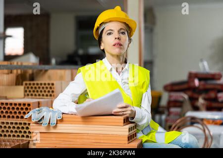 Female supervisor taking notes while inspecting construction site indoors Stock Photo