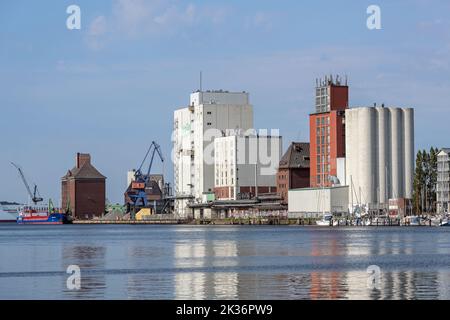 Flensburg, Germany, July 25, 2022:  Industrial city port with storage buildings and silos on the Flensburg fjord on the Baltic Sea, blue sky, copy spa Stock Photo