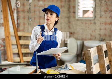 Female foreman making task list during works in building under construction Stock Photo