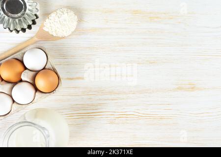 Baking cooking Ingredients background with copy space. Flour, eggs, milk, bakeware on white wooden surface. Top view, flat lay. Mockup menu, banner, h Stock Photo