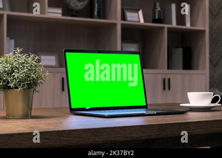 Laptop with green screen on the table. Stock Photo
