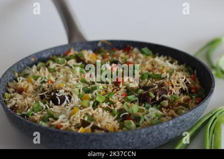 Meat rice vegetables in a pan. Cooked basmati rice tossed with sauteed vegetables and roasted mutton garnished with spring onions. Shot on white backg Stock Photo
