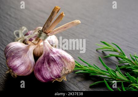 Spices for cooking. Garlic and rosemary lie on a black background Stock Photo