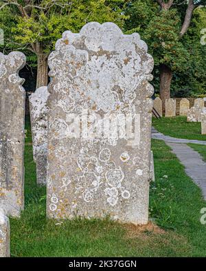 Old lichen covered gravestones in a churchyard in East Sussex UK Stock Photo