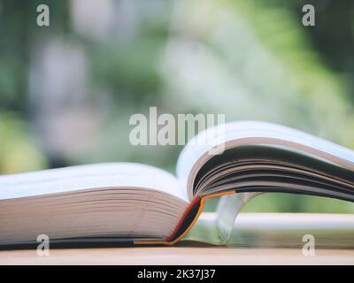 Open hardcover book for education on the table in garden. Stock Photo