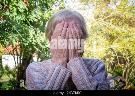 old woman covering her face with her hands Stock Photo
