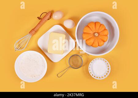 Pumpkin pie ingredients and baking tools on yellow background Stock Photo