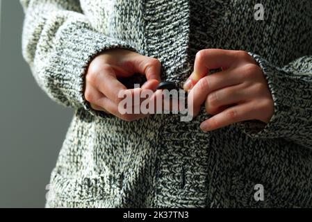 close-up of young woman in warm wool cardigan preparing for cold winter with gas and electricity shortage due to Russia Ukraine war Stock Photo