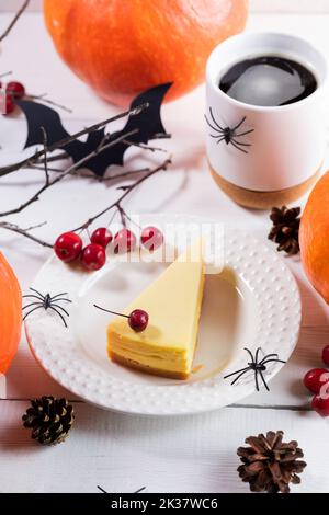 Halloween composition with sweet pumpkin cake piece, cup of te or coffee, wild apples, pumpkins, festive decorations black spiders and owls. Table set Stock Photo