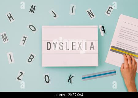 Dyslexia awareness, help children with reading, learning difficulties concept. Kid reading text using colored rulers overlays strips. Lightbox with Stock Photo