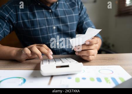 Young asian man calculating expenses household about finance and frustrated on desk at home, male checking bill having stress and worried, debt and Stock Photo
