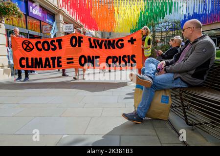 Bath, UK. 25th Sep, 2022. With PM Liz Truss signalling an acceleration of oil and gas extraction in the UK shoppers look on as climate change protesters take part in a protest march through the centre of Bath. The protest organised by Extinction Rebellion was held in order to highlight how the cost of living crisis and the climate crisis are interlinked. Credit: Lynchpics/Alamy Live News Stock Photo