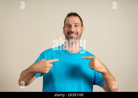 Photo portrait of confident smiling bearded hispanic man pointing at himself isolated on beige background. Stock Photo