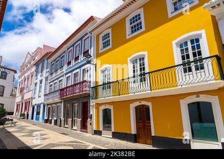 The colorful pastel facades of the neoclassical style buildings along the pedestrian walkway of the Rua da Esperanca ending at the pink Teatro Angrense, a performance art theatre in Angra do Heroismo, Terceira Island, Azores, Portugal. Stock Photo