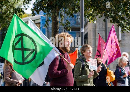 Bath, UK. 25th Sep, 2022. With PM Liz Truss signalling an acceleration of oil and gas extraction in the UK, climate change protesters carrying Extinction Rebellion flags are pictured as they listen to speeches outside Bath train station before taking part in a protest march through the centre of Bath. The protest organised by Extinction Rebellion was held in order to highlight how the cost of living crisis and the climate crisis are interlinked. Credit: Lynchpics/Alamy Live News