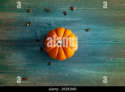 orange pumpkin on blue and colorful wooden background, ideal as a background for Halloween or autumn theme, orange pumpkin isolated Stock Photo