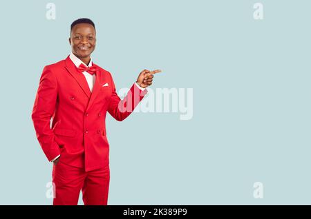 Friendly cool African American man in fashionable suit presents advertising product. Stock Photo