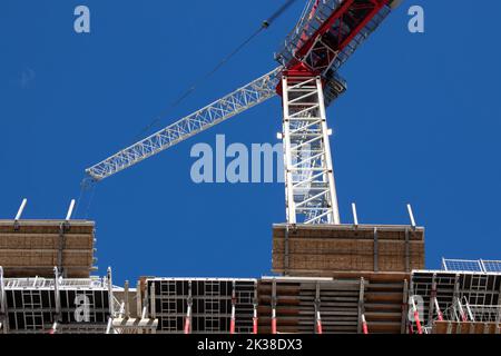 A construction crane is seen on a clear sky day, while on-site building a condo, apartment building. Stock Photo