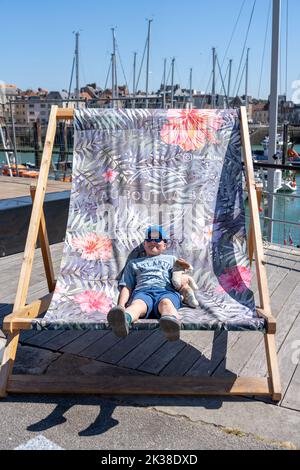 Young boy sitting in a giant deckchair Stock Photo