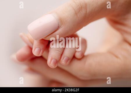 Close-up of a baby's small hand with tiny fingers and arm of mother. Stock Photo