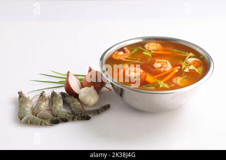 Tom Yam kung Spicy Thai soup with shrimp, seafood, and chili pepper in bowl on white background in a steeliness steel bowl Stock Photo
