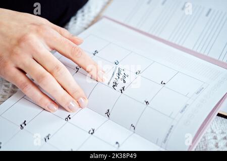 Planner calendar with text Job interview on date. Female hands writing Job Interview Date on a Calendar. Woman write in print calendar with mark and Stock Photo