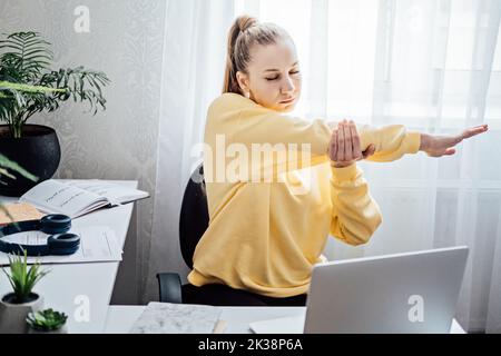 Workout at work. Office Exercises at desk, Desk Friendly Workplace Exercises To Keep Healthy at Office. Young woman office worker at her workplace Stock Photo