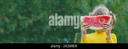 child eats a watermelon in the garden. Selective focus. Stock Photo