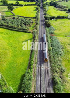 Bonvilston, Vale of Glamorgan, Wales - September 2022: Aerial view of a commuter train on a main railway line through countryside near Cardiff